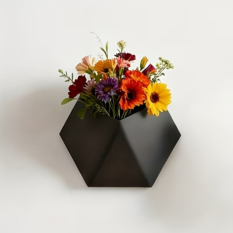 Black hexagonal wall planter with mounting holes, holding bright mixed flowers