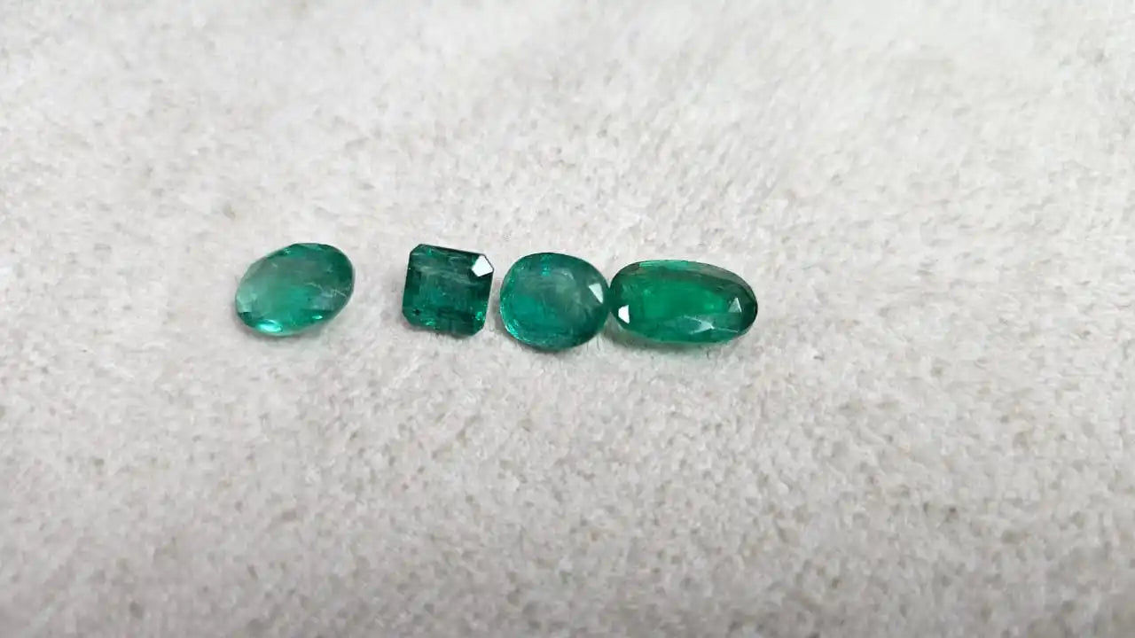 Loose green emerald-cut gemstone mix, small oval and rectangular stones on felt