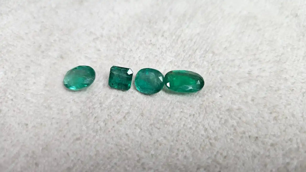 Loose green emerald-cut gemstone mix, small oval and square cuts on felt
