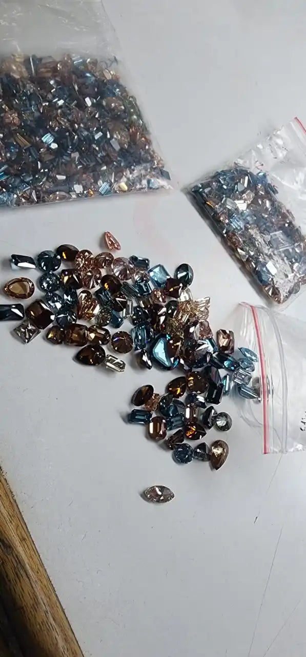 Loose faceted lab-grown diamond stones in mixed blue, brown, and dark tones