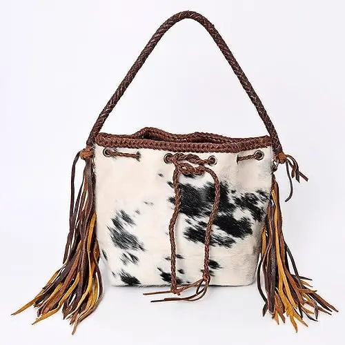 Vintage cow print cowhide bucket bag with fringe, brown braided handle, and drawstring closure for stylish ladies.