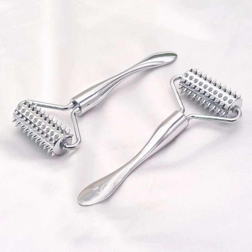 Two silver metal facial massage rollers with spiked textures for skin stimulation on a white fabric background.