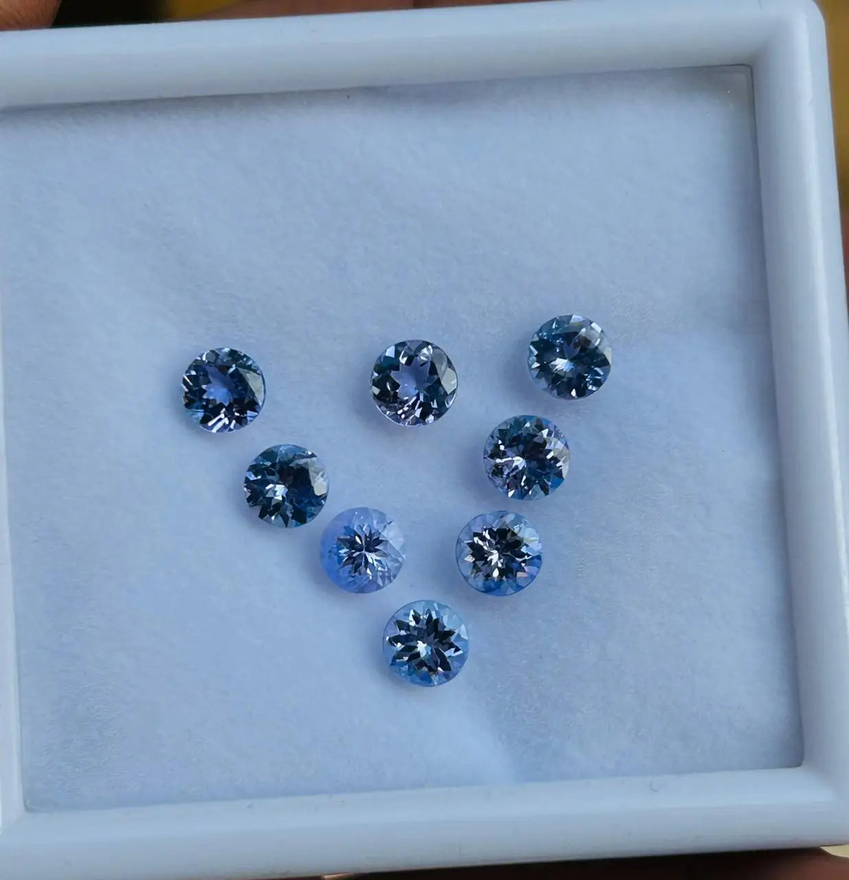 Blue round faceted gemstones in a white display tray