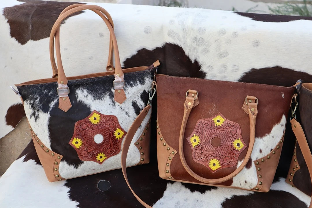 Western fur leather handbags with tooled floral patches, zipper closure, stud accents, and removable shoulder straps.