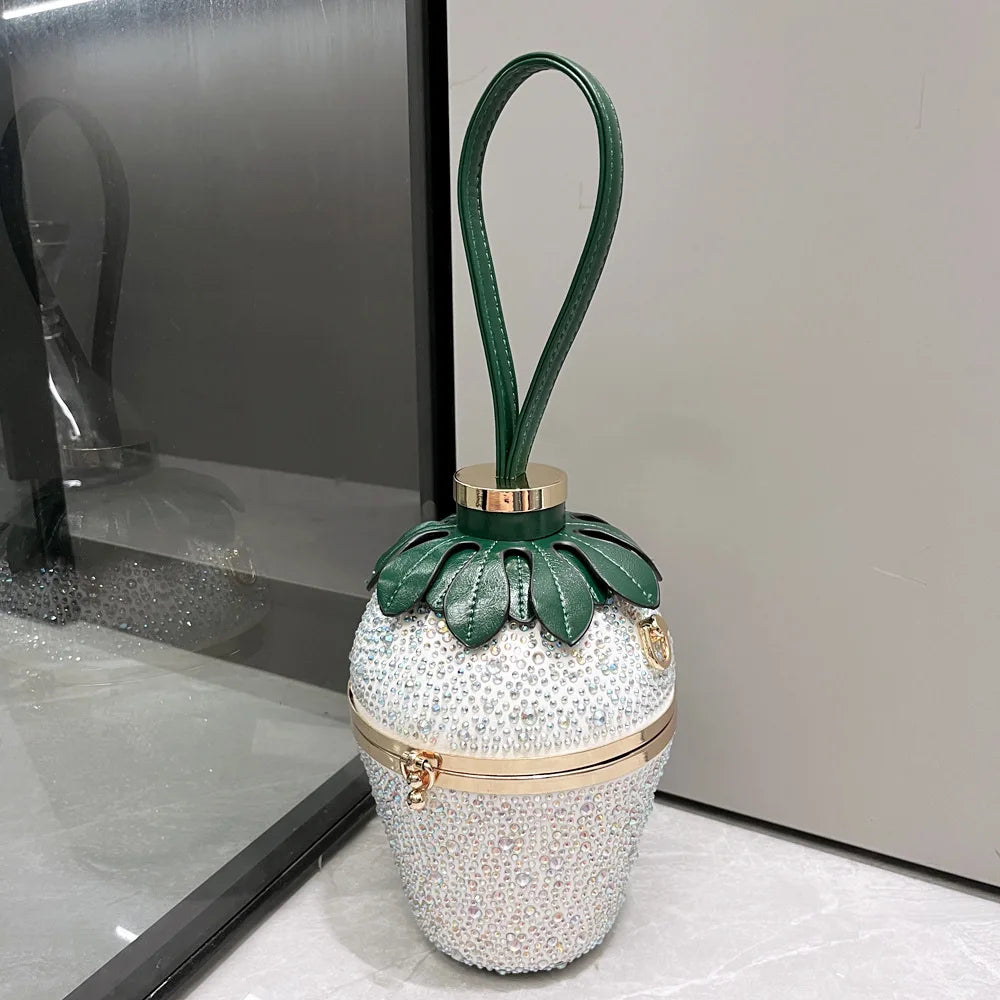 Rhinestone strawberry-shaped evening handbag with green leather leaves, gold accents, and a wrist strap.