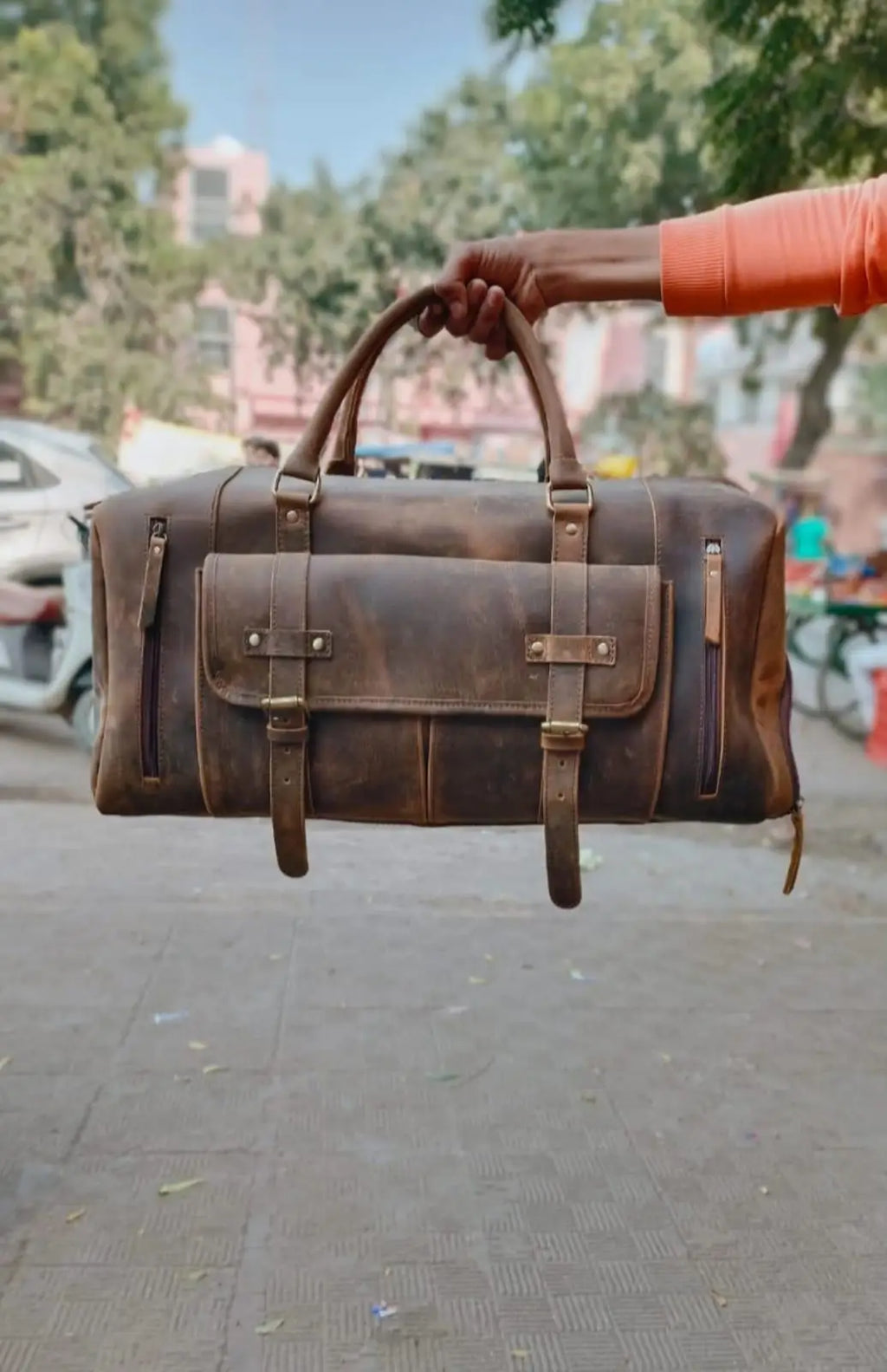 Brown full grain leather trunk gym bag with front buckled pockets, dual handles, and side zippers for travel or sports.