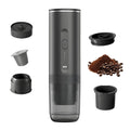 Matte black portable electric espresso maker with capsule and ground coffee attachments, USB charging, isolated white.
