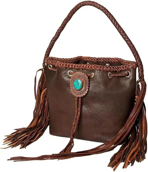 Brown leather bucket bag with braided strap, side fringe, and turquoise stone embellishment in a vintage trunk style.