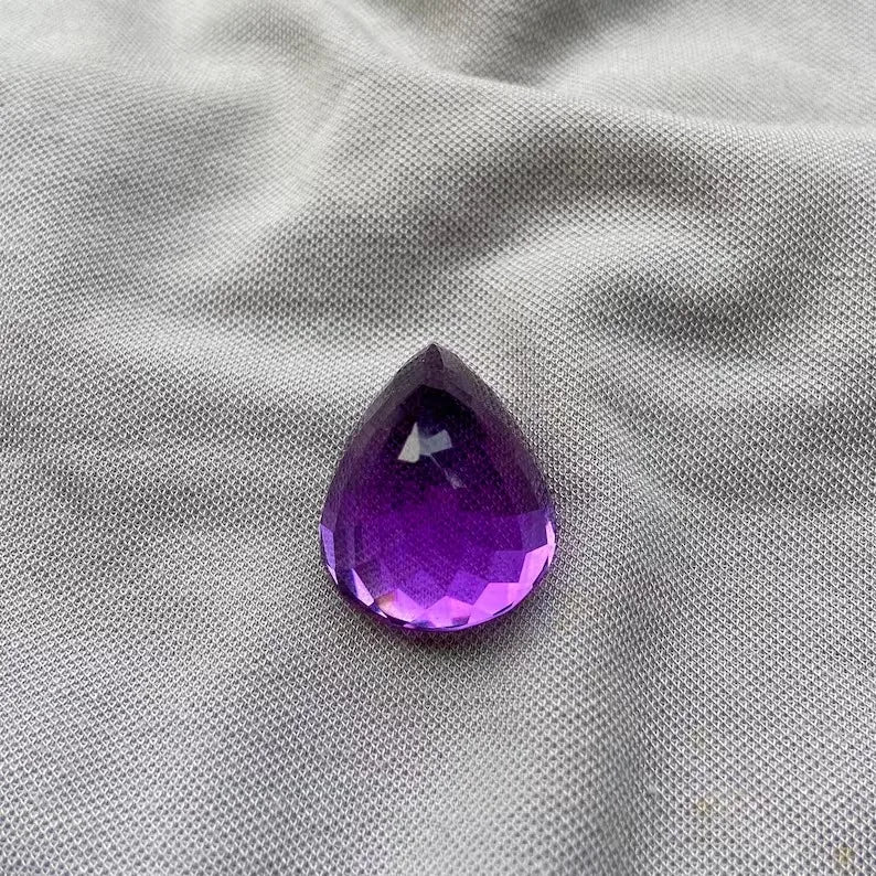Amethyst teardrop (pear) gemstone with deep purple tone and pointed top facet