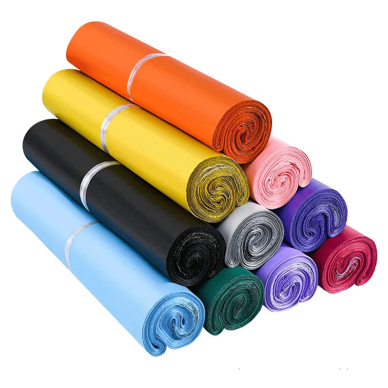 Colored waterproof poly mailer bag rolls in orange, yellow, black, and blue tones