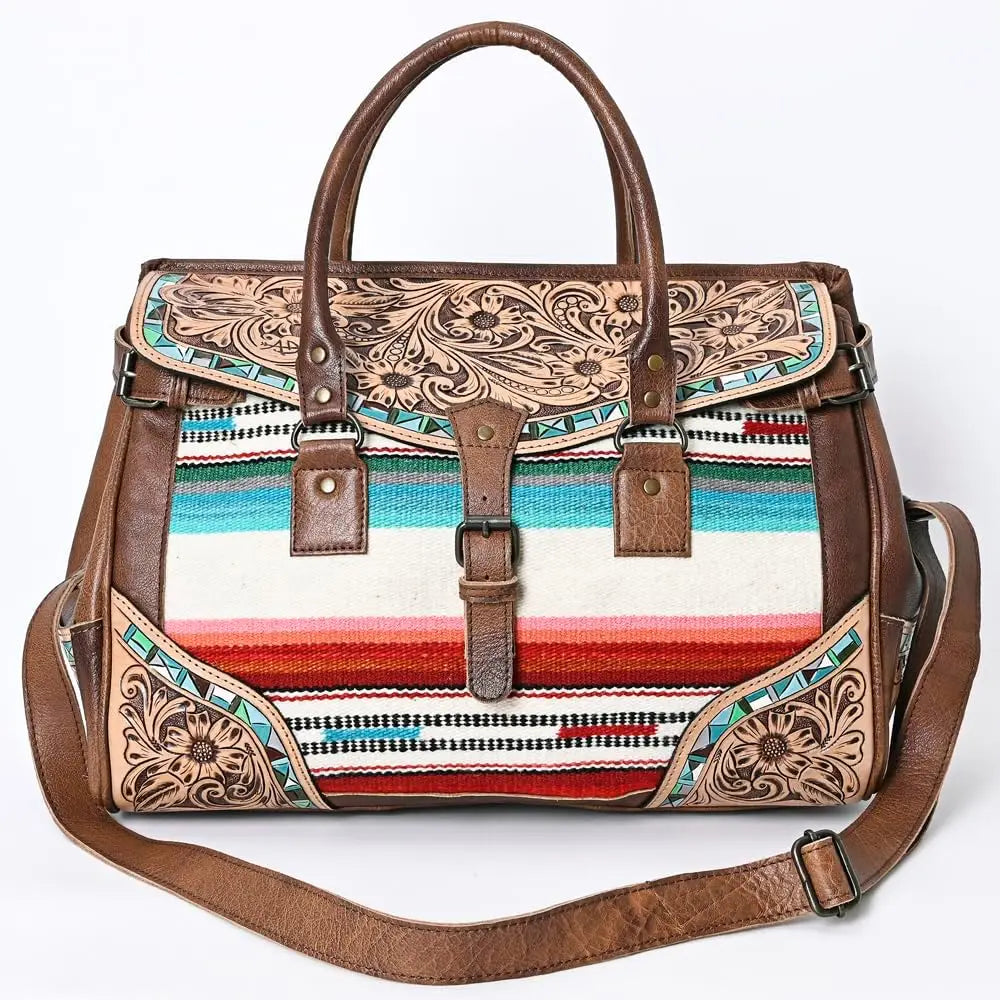 Handwoven colorful striped textile and brown tooled leather duffel bag with floral embossing for travel.