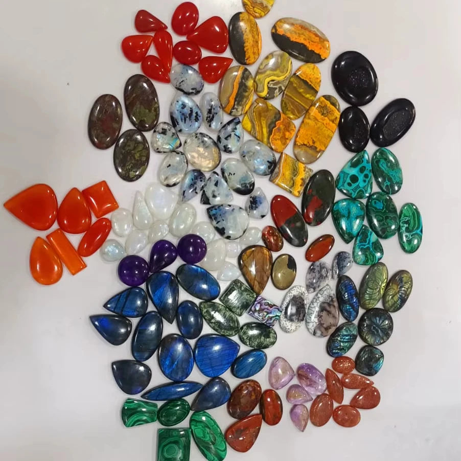 Mixed-shape cabochon gemstone assortment, glossy red, blue, green, and purple stones