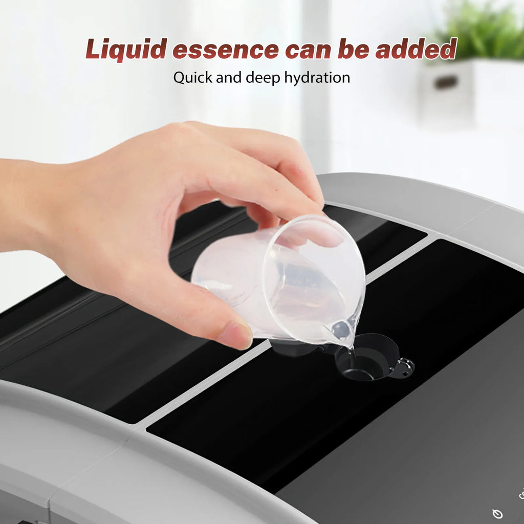 A hand pours liquid essence from a small clear plastic cup into the refill port of a gray and black humidifier.