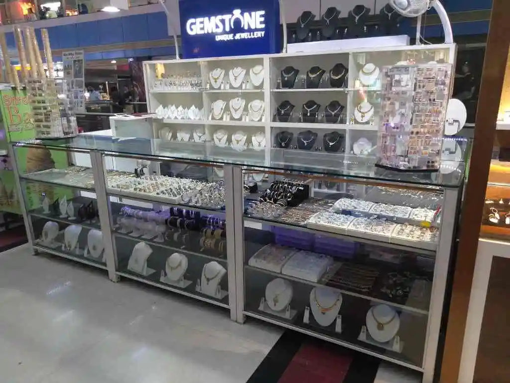 Glass jewelry display case with necklaces and gemstone settings