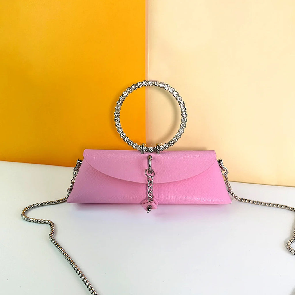 Pink PU leather clutch bag with rhinestone ring handle, silver chain strap, and elegant evening trunk design.