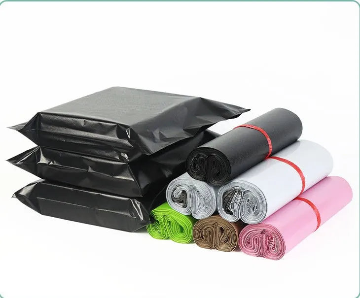 Assorted rolls of plastic mailing bags: black, white, pink, and green with red bands