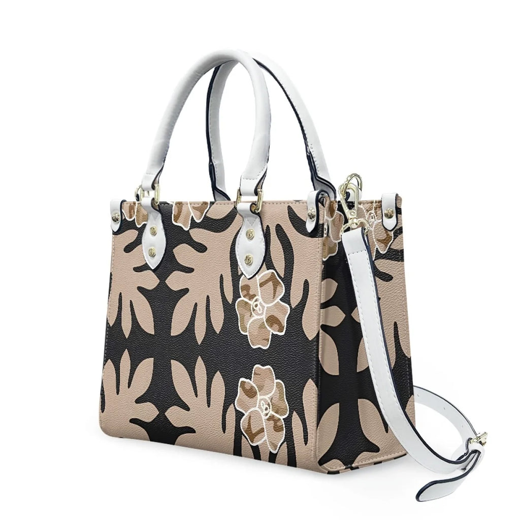 Luxury leather shoulder bag featuring beige and black Polynesian tribal floral patterns with white handles and strap.