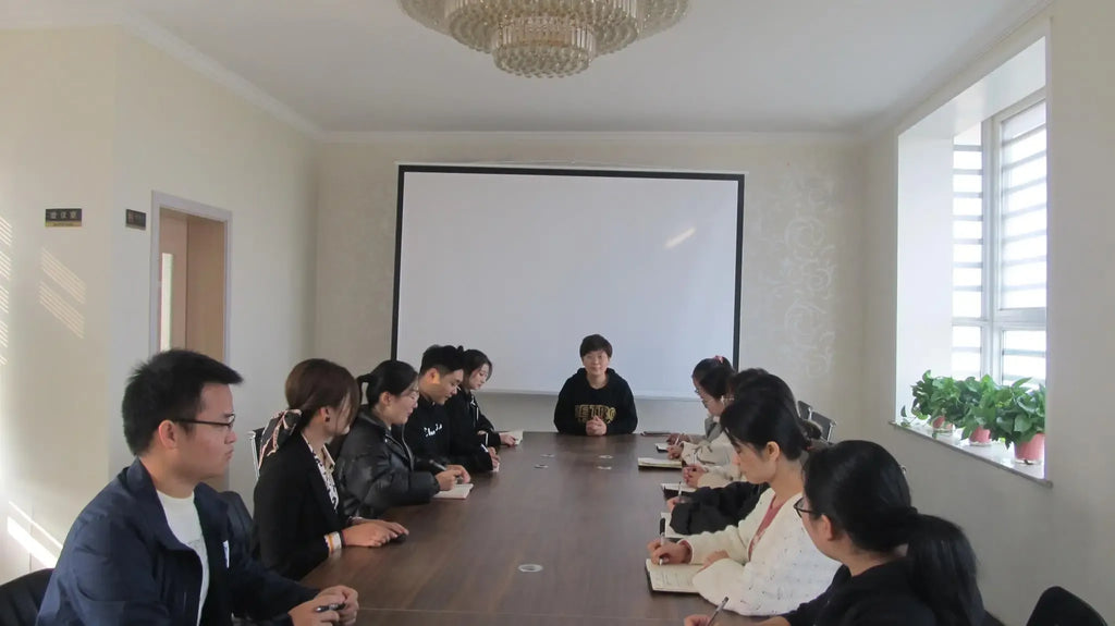 Conference room with people seated around a table using laptops