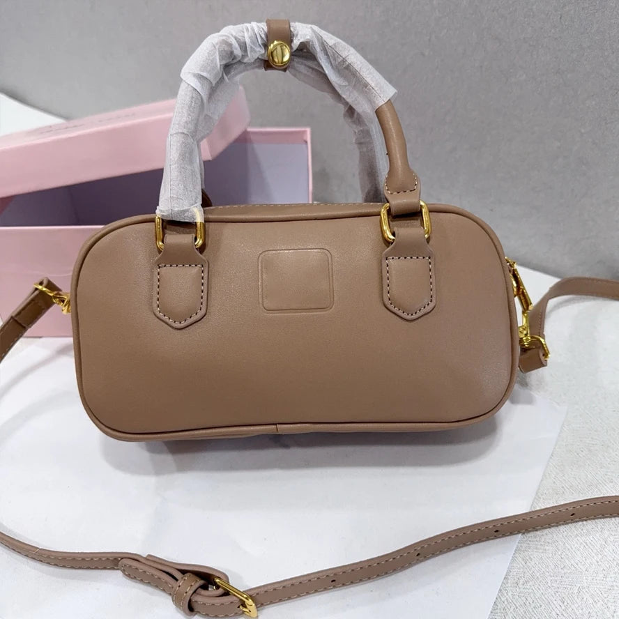 Taupe luxury designer trunk handbag with gold hardware, leather material, top handle, and detachable shoulder strap.