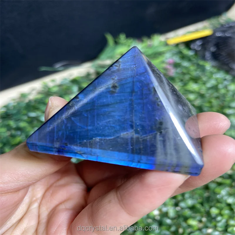 Blue labradorite flash pyramid crystal paperweight held in hand, glossy pointed top