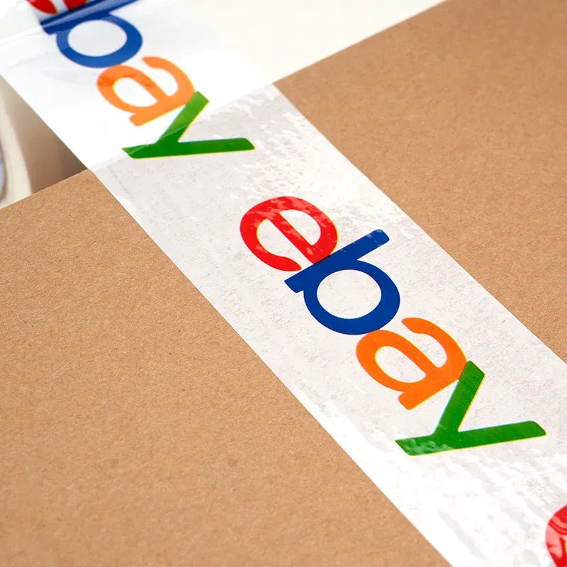 Close-up of white packing tape strip with colorful eBay logo print on shipping surface