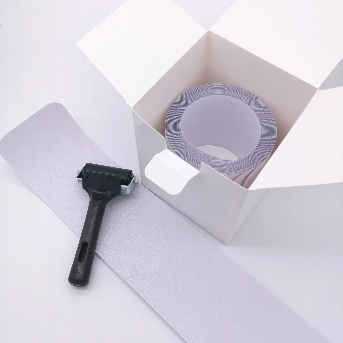 Clear anti-slip tape roll with applicator tool beside bathtub safety strips