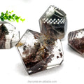 Polished clear quartz free-form crystal with dark mineral flecks and reddish-brown patches