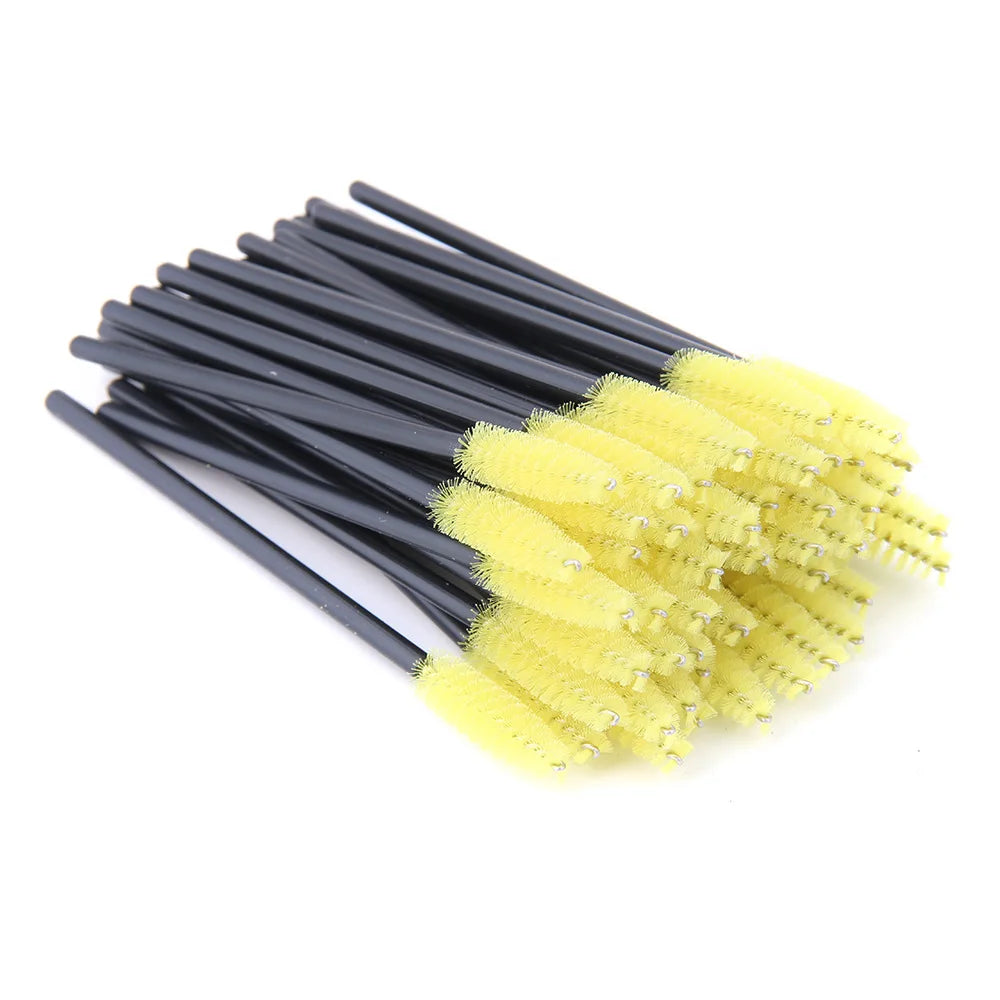 Disposable mascara wands with bright yellow bristle heads and long black plastic handles for applying lash extensions.
