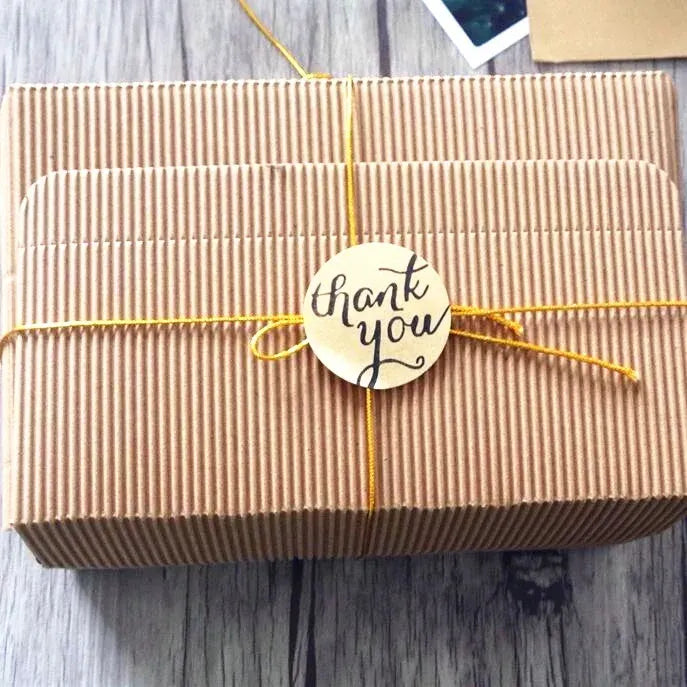 Straw-wrapped gift box with a round “thank you” adhesive seal sticker in center.