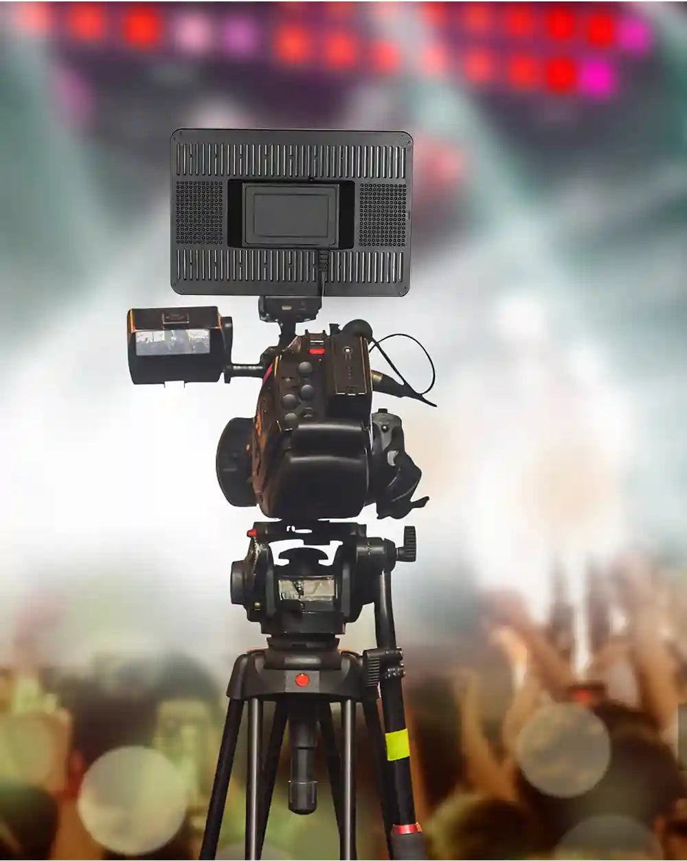 Professional video camera with attached LED light panel mounted on a black tripod for filming events.