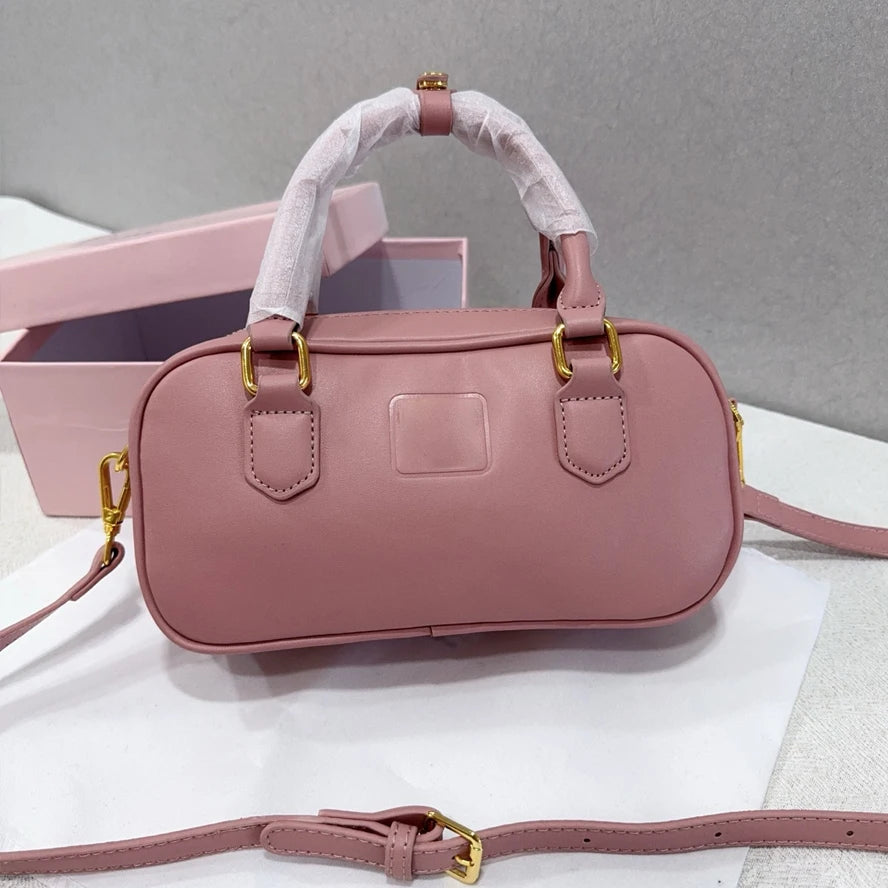 Dusty pink leather luxury trunk handbag with gold hardware, top handles, and detachable crossbody shoulder strap.