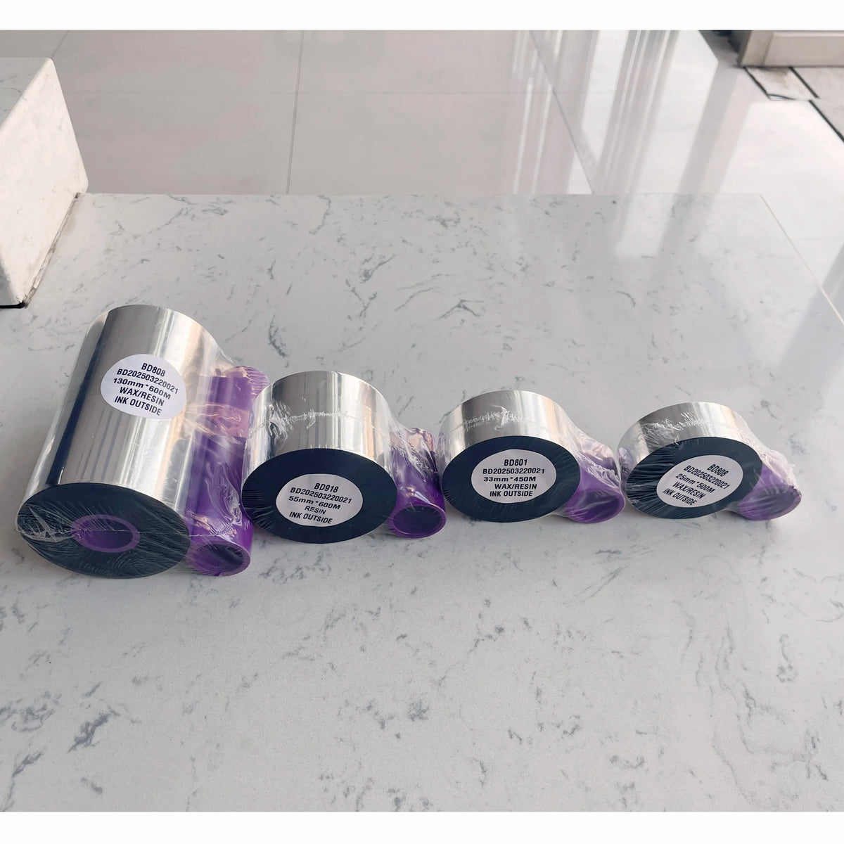 Black TTO thermal ribbon rolls on reflective silver cores with purple edge wrap