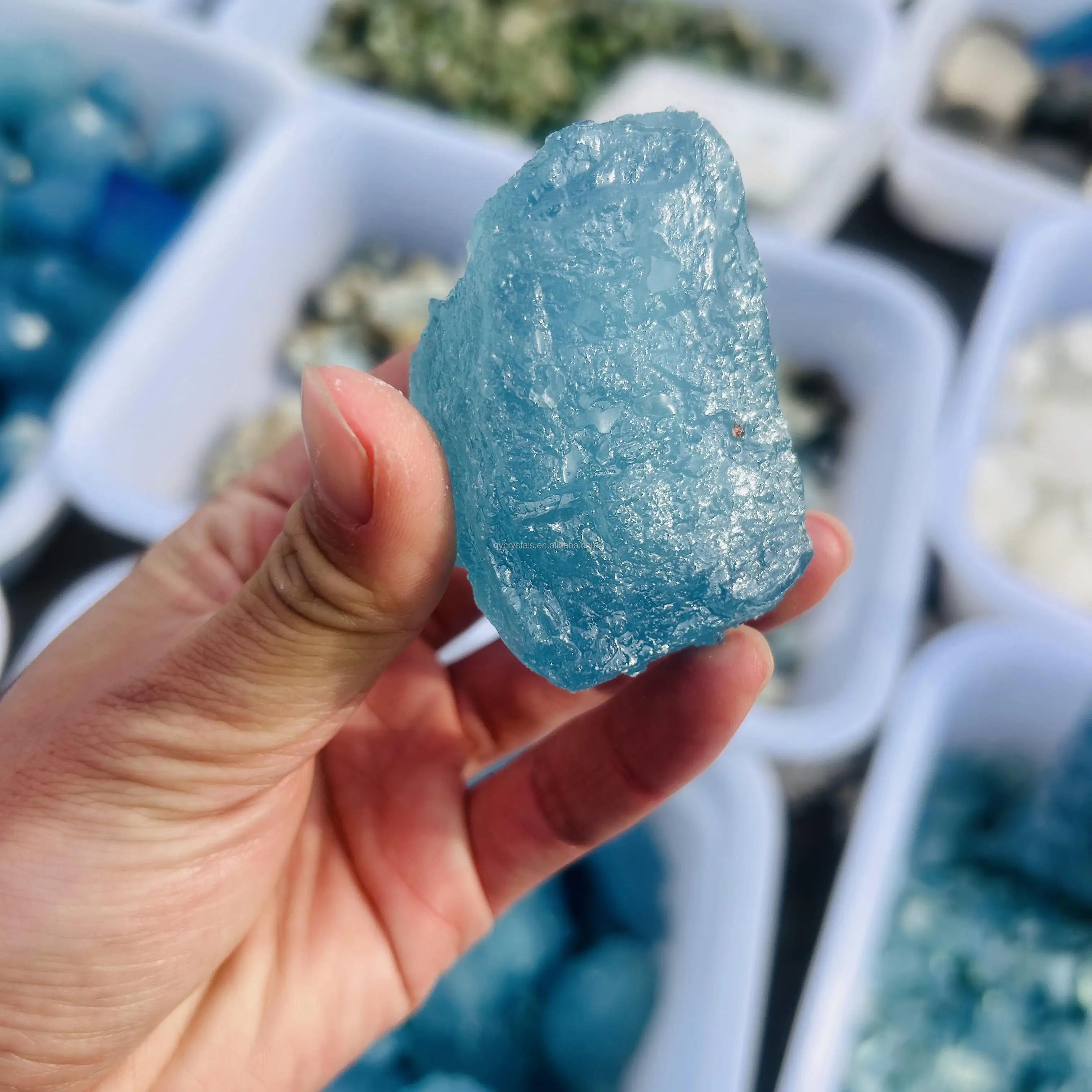 Sky blue aquamarine rough crystal stone, jagged druzy face, held up