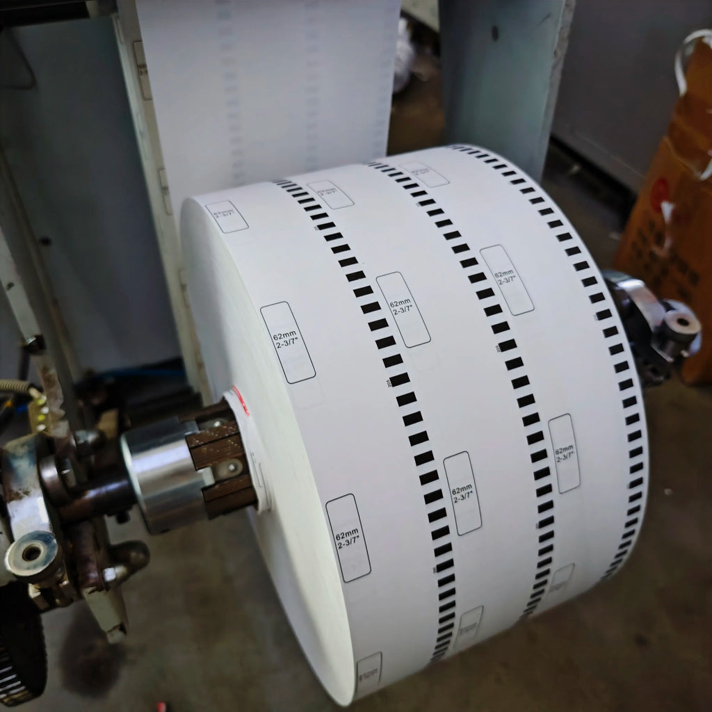 White continuous label roll inside printer, showing black dashed border guides