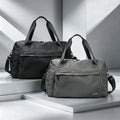 Black and grey waterproof nylon travel duffel bags with zippered pockets, dual handles, and adjustable shoulder straps.