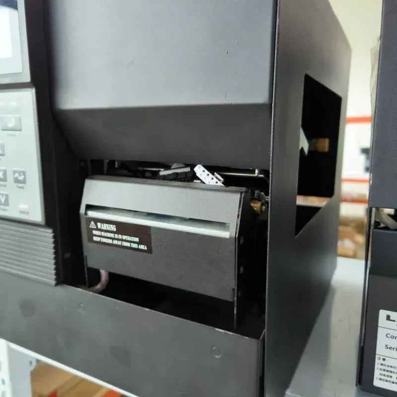Close-up of black thermal transfer printer interior and print head area behind front panel