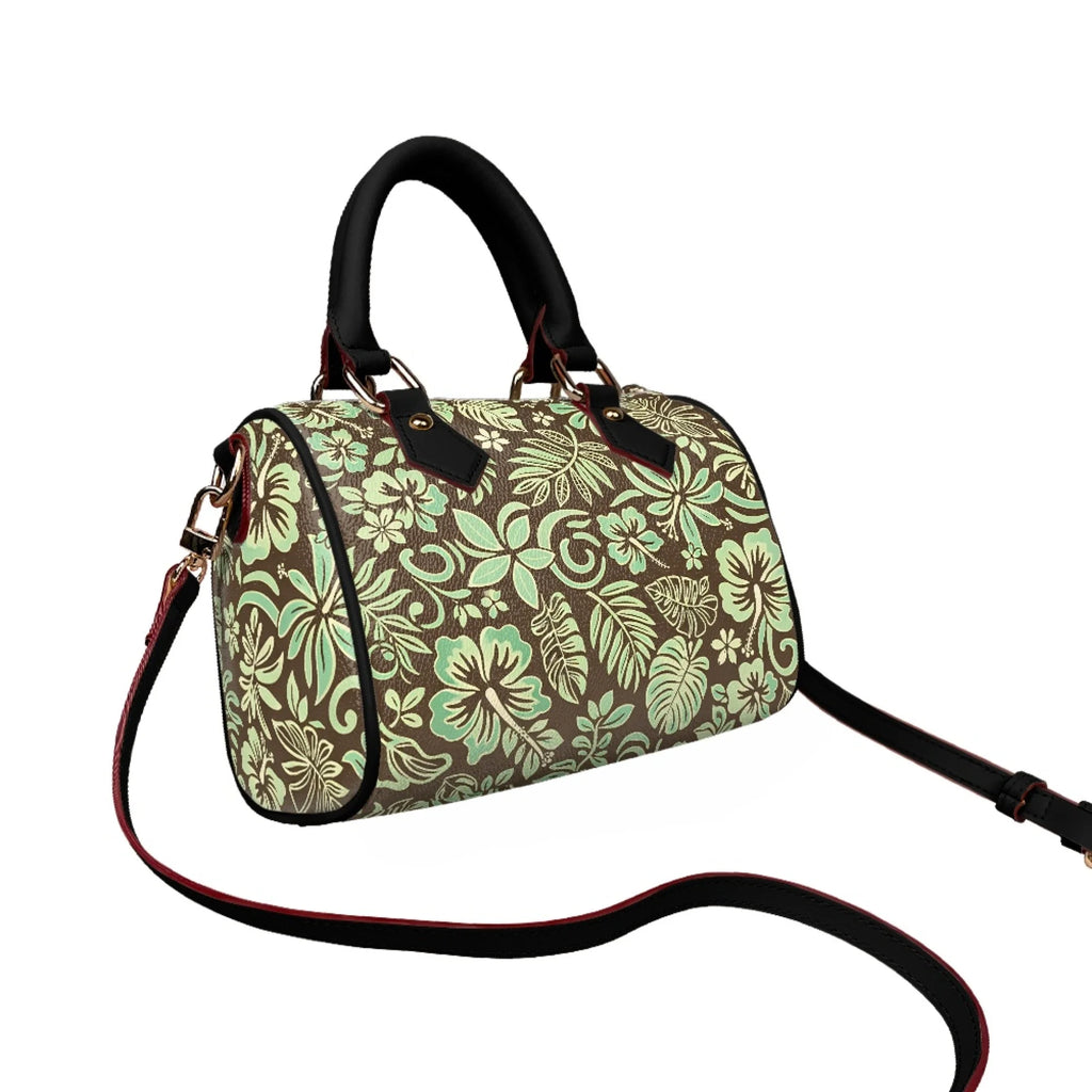Pillow-shaped trunk handbag in brown and mint tropical floral print with black leather handles and shoulder strap.