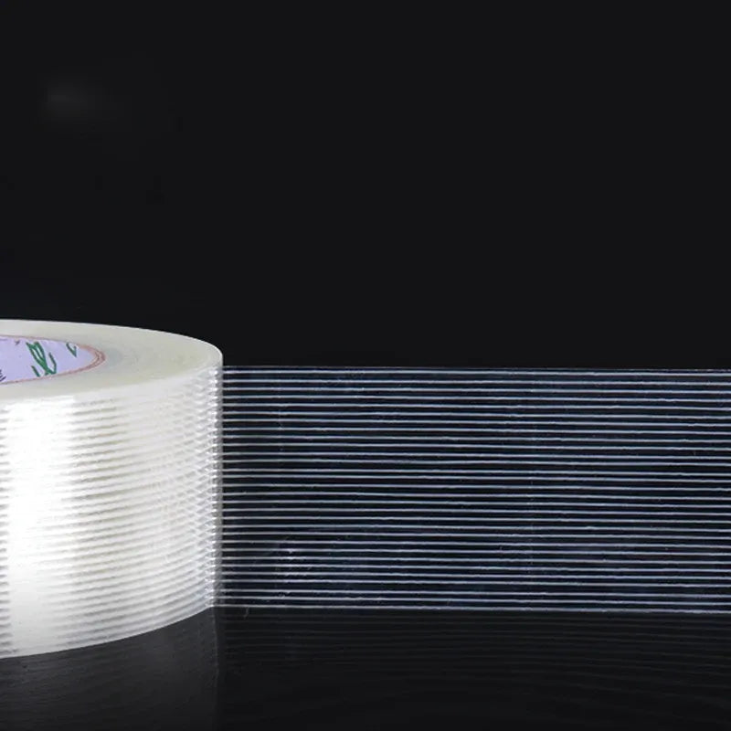 Cross-fiber filament tape strip with fine blue parallel lines next to tape roll