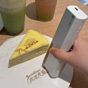 White handheld coffee inkjet printer printing on a slice of dessert