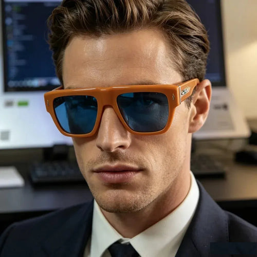 Man wearing luxury orange acetate square sunglasses with blue tinted lenses in an office setting.