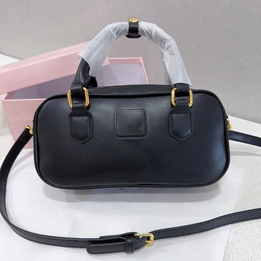 Black leather trunk handbag with gold hardware, top handles, and adjustable shoulder strap, luxury designer style.