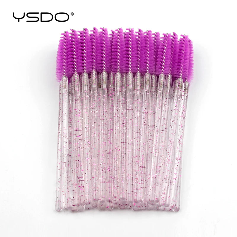 Disposable spoolie brushes with bright purple heads and clear plastic handles containing pink glitter, for mascara.