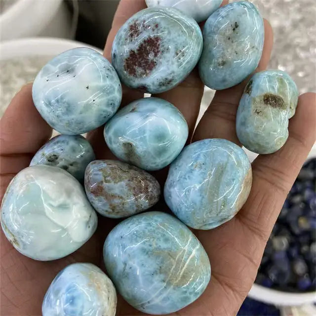 Sky blue tumbled larimar gemstones with visible dark specks and white striations