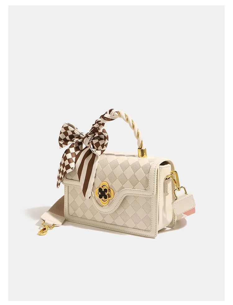 Beige plaid luxury leather trunk handbag with gold clasp, top handle, and brown checkered silk scarf accessory.