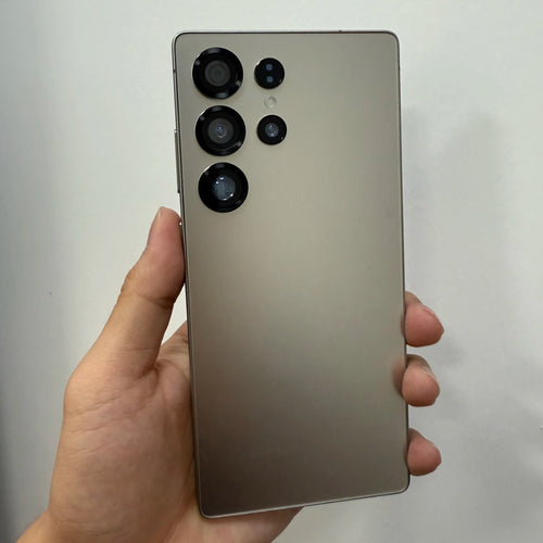 Gray smartphone back with quad camera module, held in hand.
