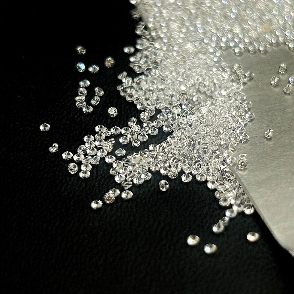 Loose round brilliant lab-grown diamonds spilled, tiny round facets on surface