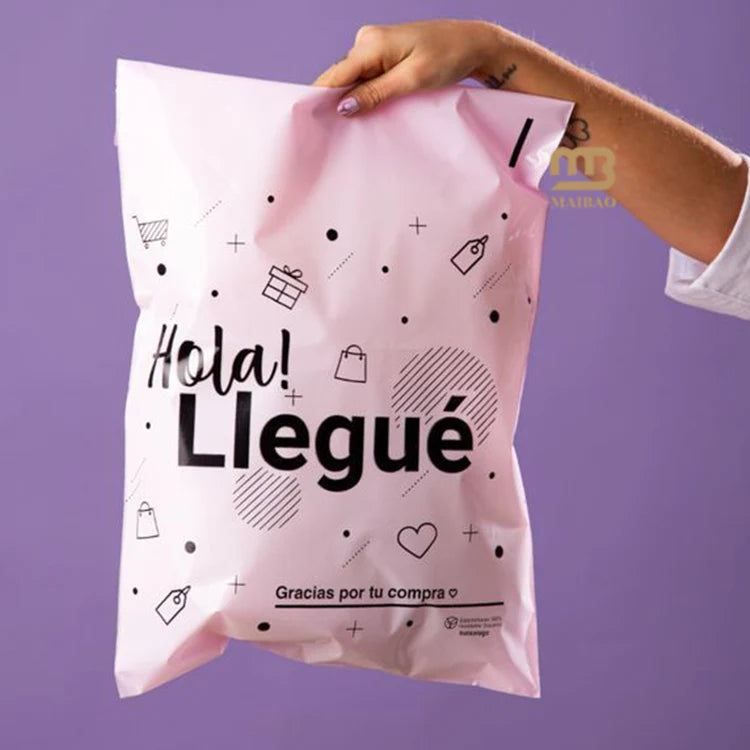 Pink poly mailer with printed greeting and icons, held by a hand