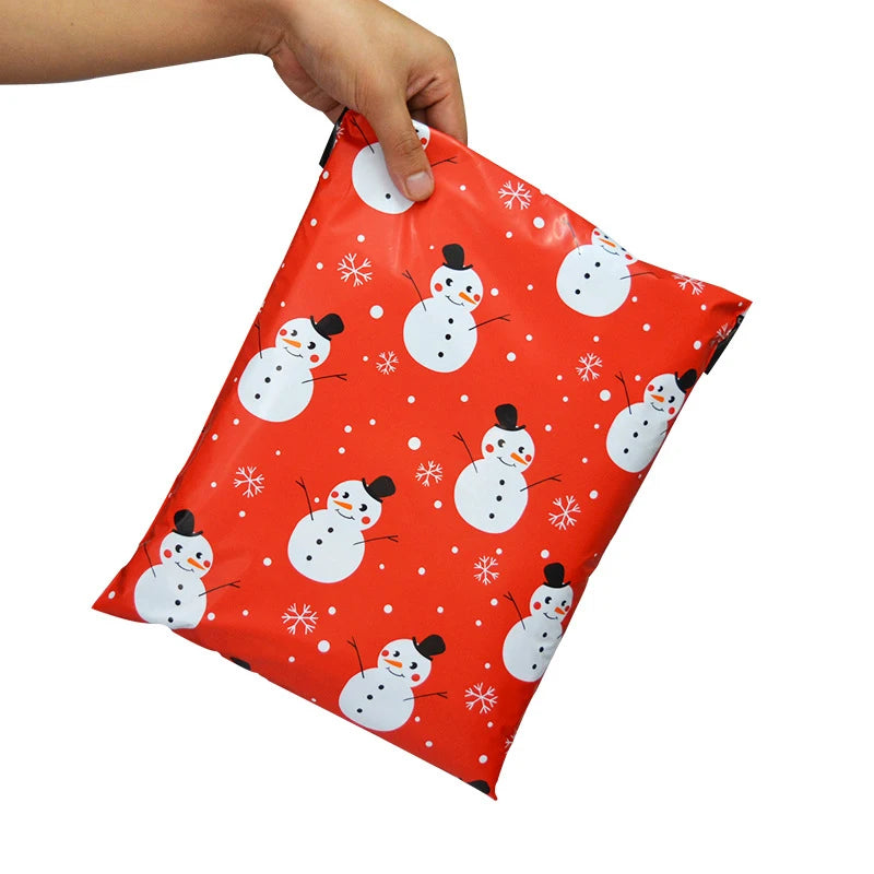 Red waterproof poly mailer held by fingers, snowman and snowflake print