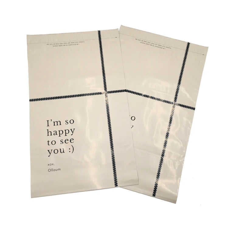 Cream poly mailer bags with black dotted border lines and printed "I'm so happy to see you"