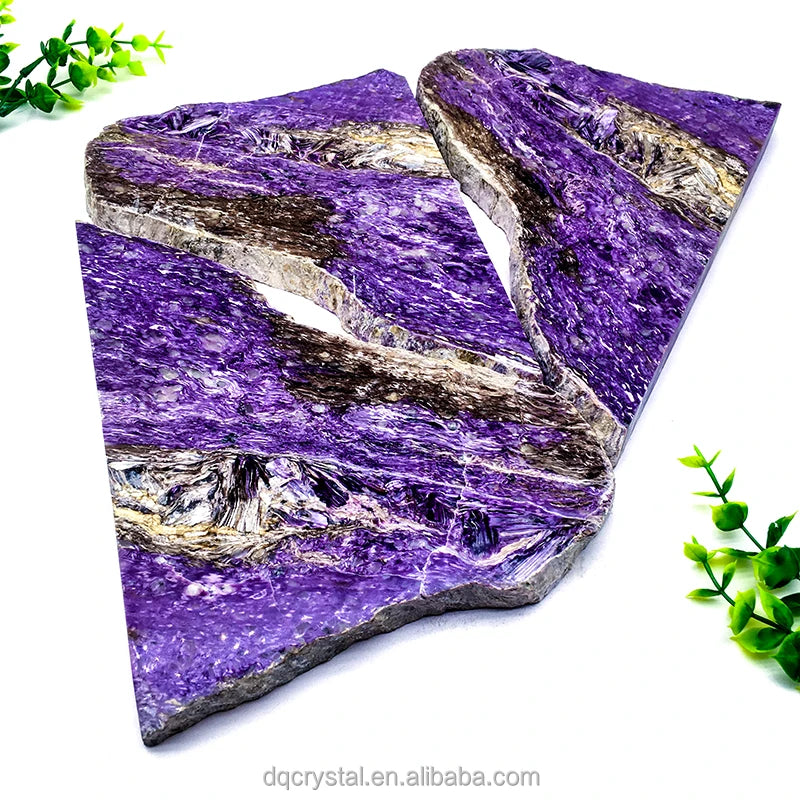 Polished purple charoite slice stone with irregular layered facets and light stone bands